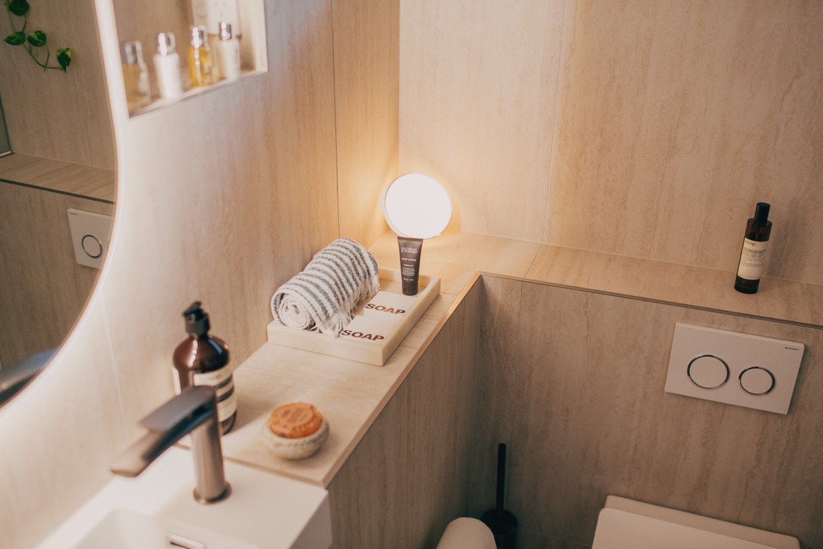 Renovated bathroom with timber vanity, round mirror and warm lighting