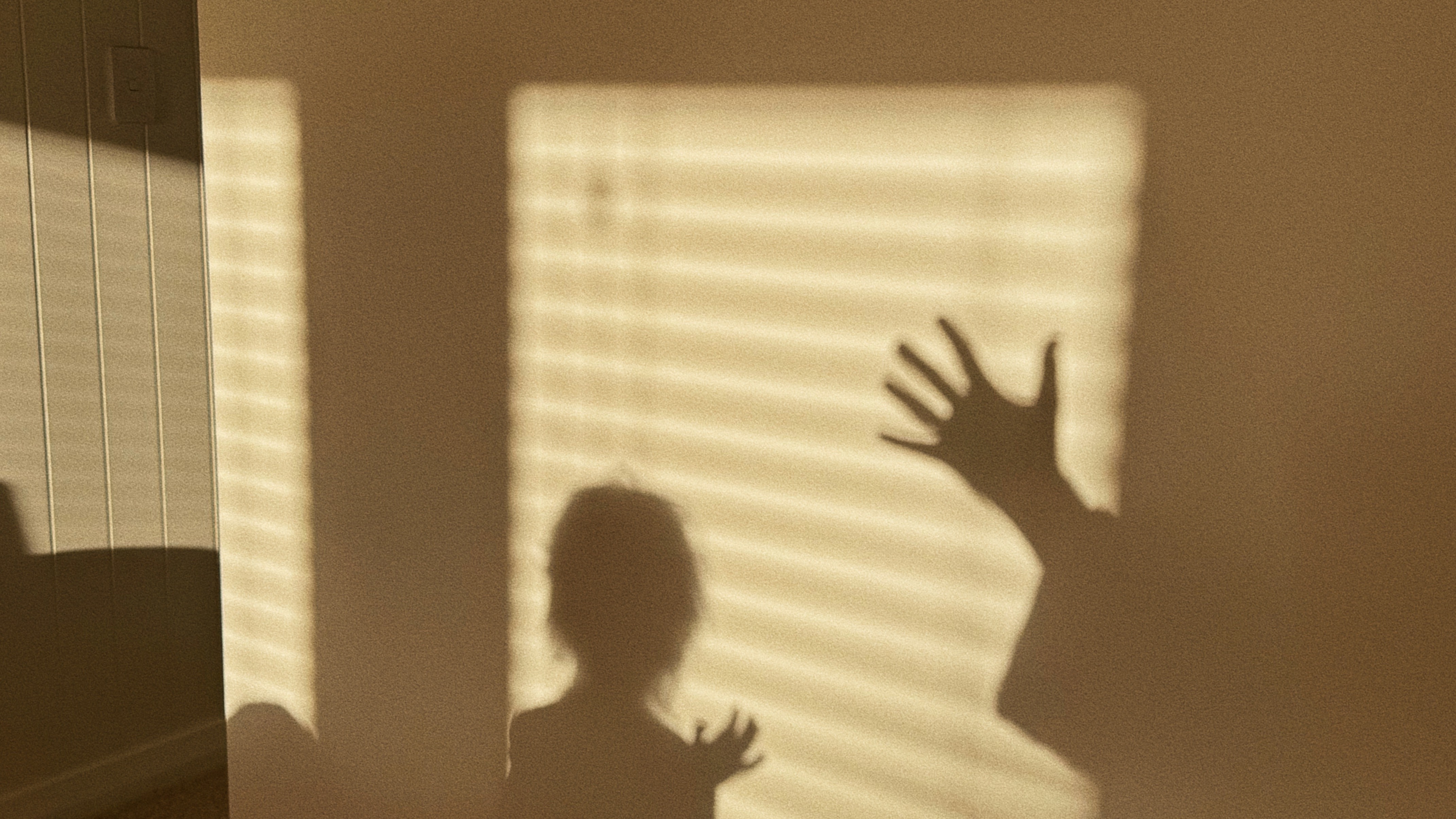 Shadow of a child playing in warm golden morning light on a bedroom wall