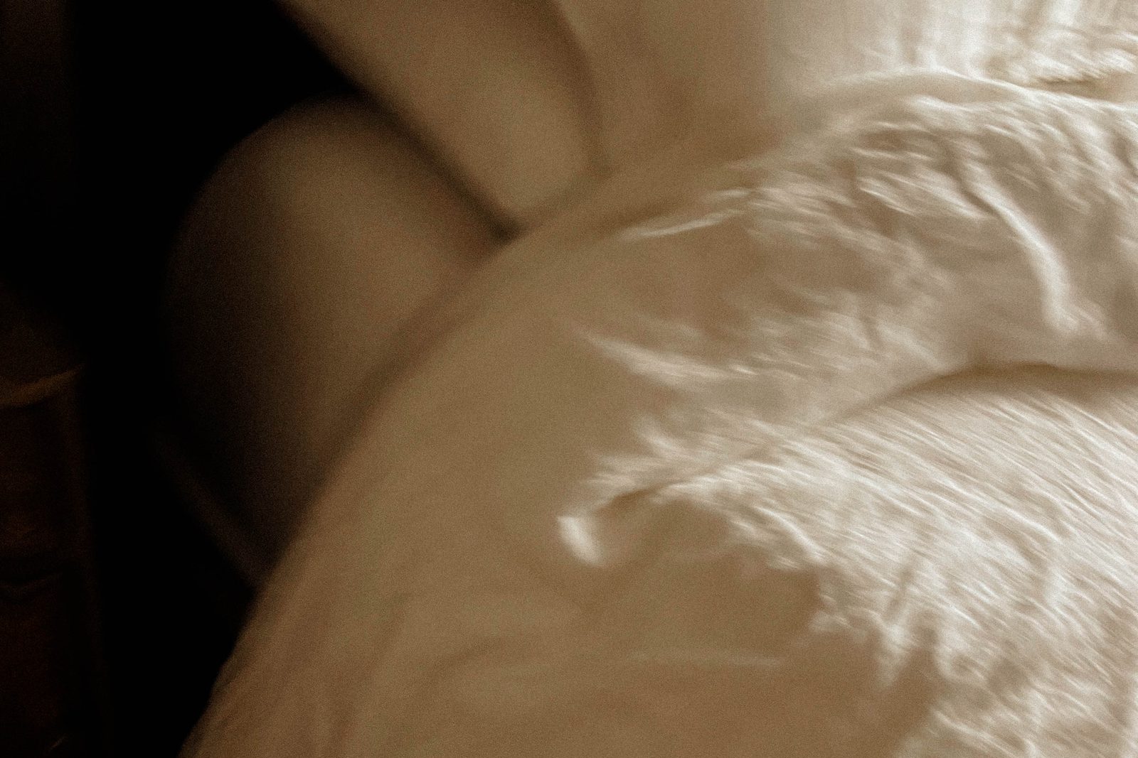 Fresh white bed linen catching soft morning light in a calm bedroom