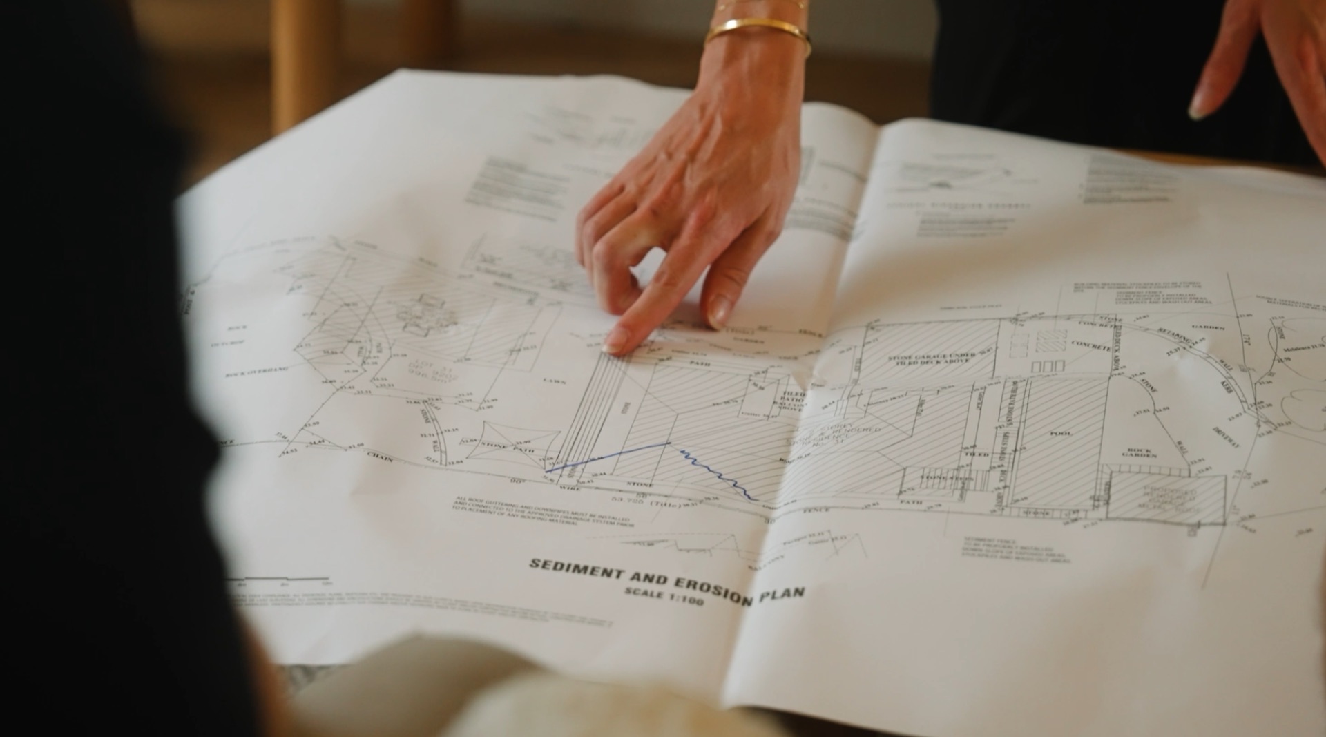 Hands reviewing detailed site plans during pre-construction