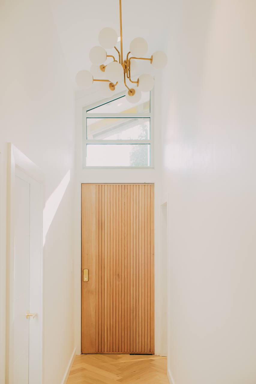 Entry hallway with a timber door and a brass pendant light in the Castle Hill home