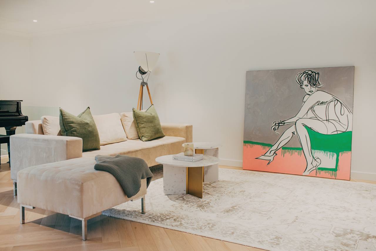 Living room in the Castle Hill home with a neutral sofa, marble coffee tables and abstract artwork