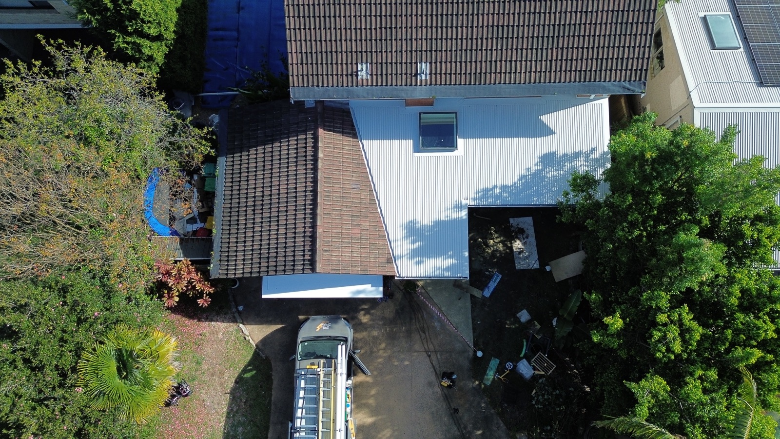 Aerial view of the finished white metal roof over the new extension beside the original terracotta tiles