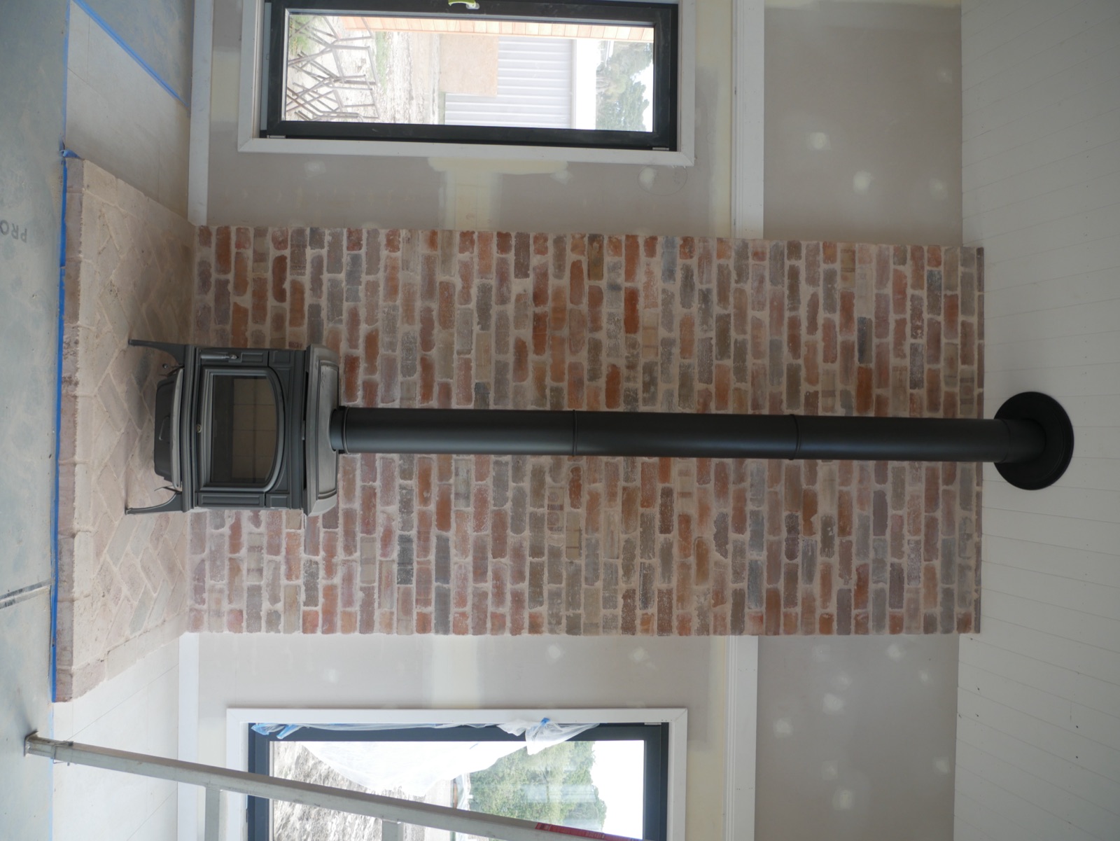 Recycled brick fireplace with a black slow-combustion wood heater and herringbone brick hearth inside the Ingleside home