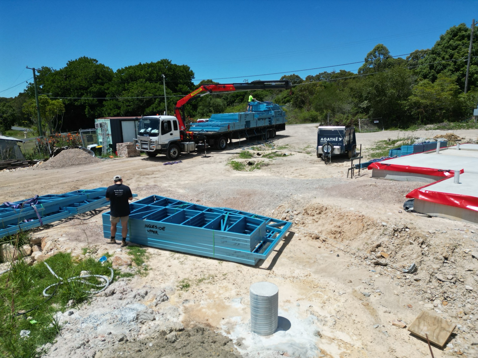 Steel wall frames being delivered by crane truck beside the concrete slab at Ingleside