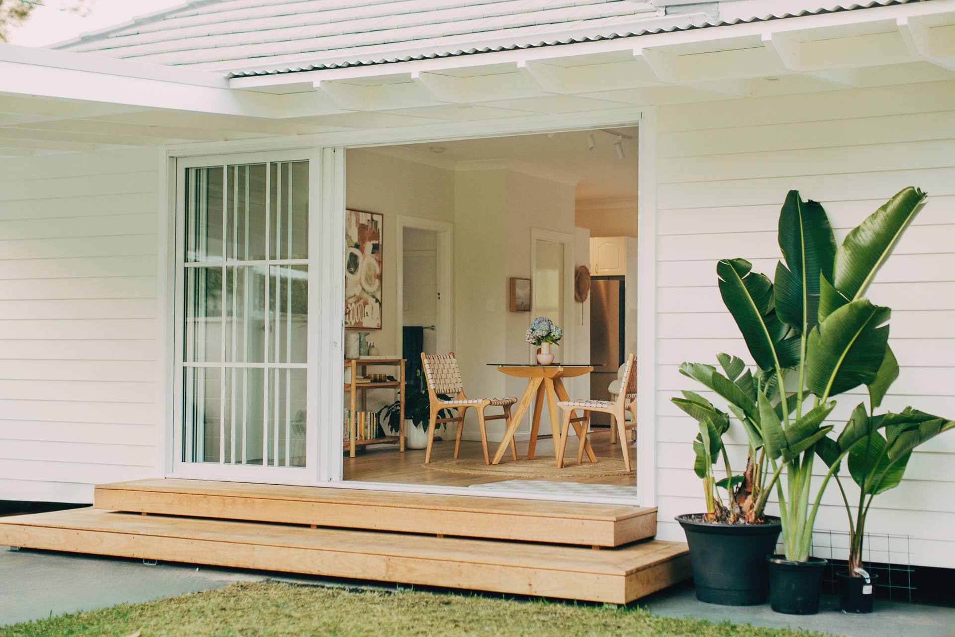 Open aluminium sliding French doors connecting the open-plan interior to the timber deck at the North Narrabeen home