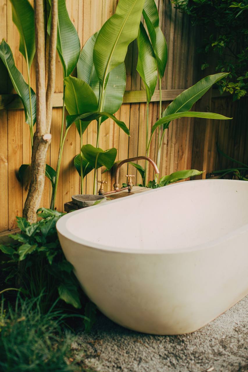 Freestanding outdoor bath framed by tropical planting at the North Narrabeen home