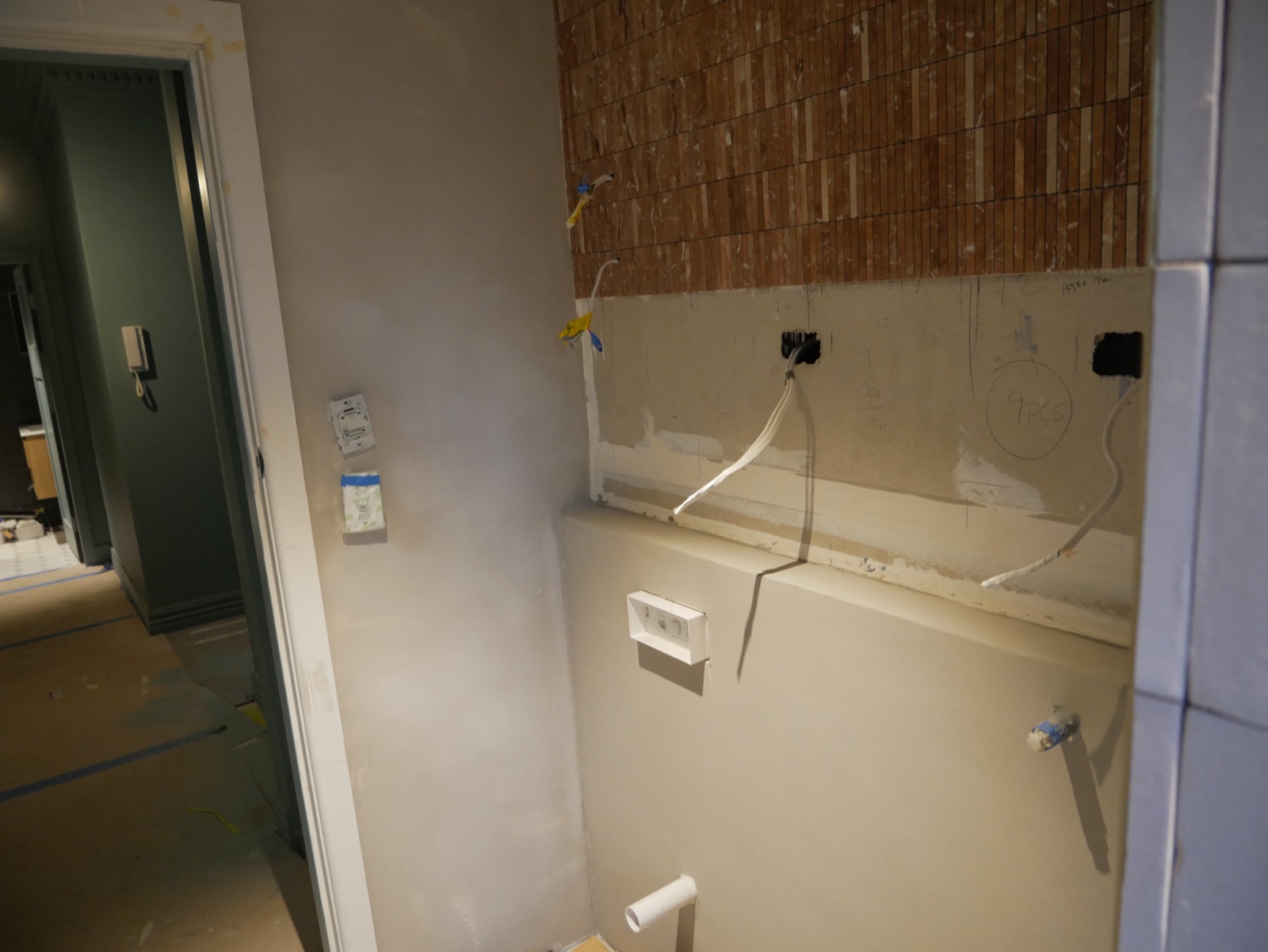 The mosaic feature wall from the design render being tiled in the Neutral Bay apartment bathroom