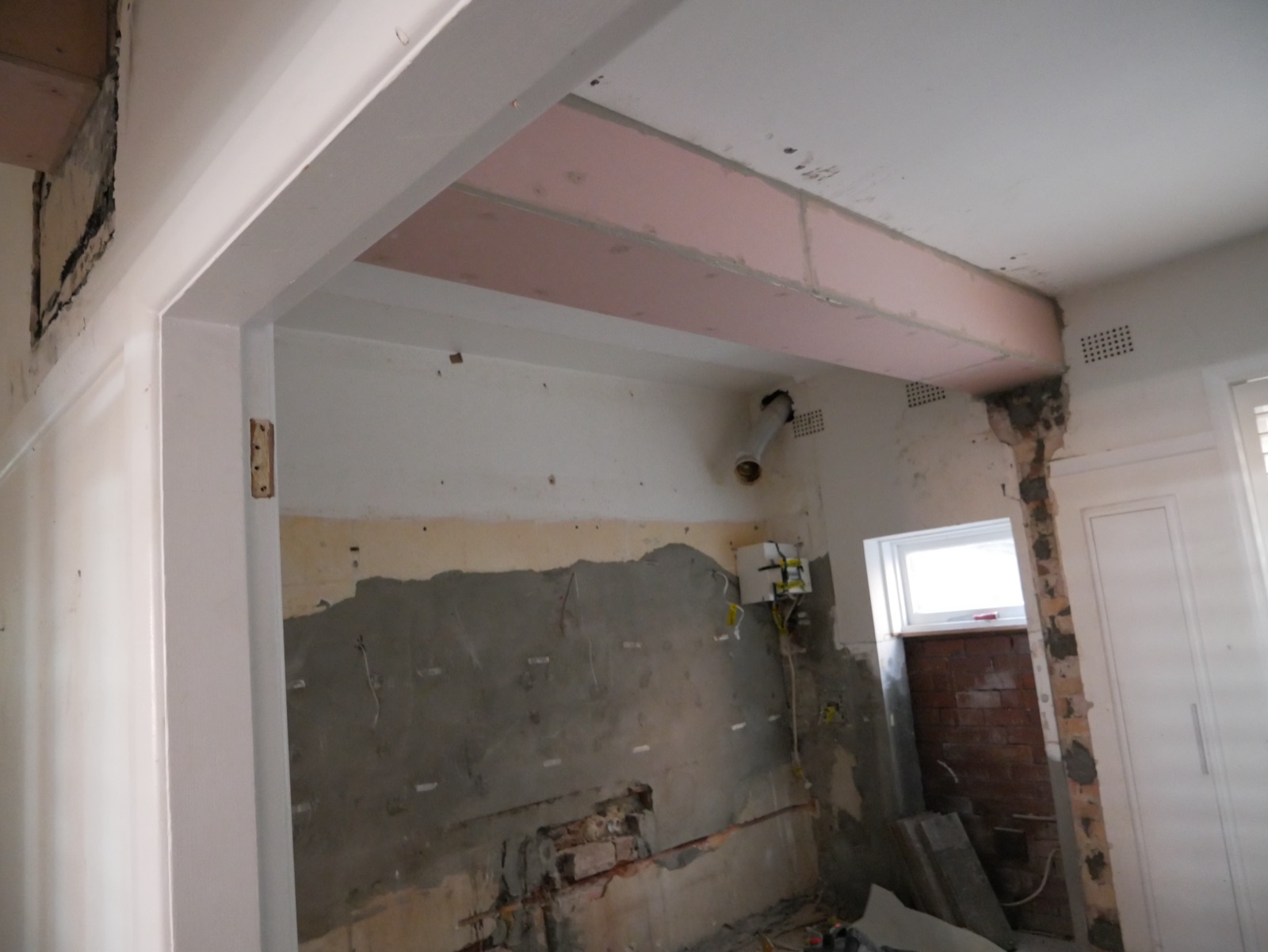 New steel beam encased in pink fire-rated plasterboard in the Neutral Bay Class 2 apartment renovation