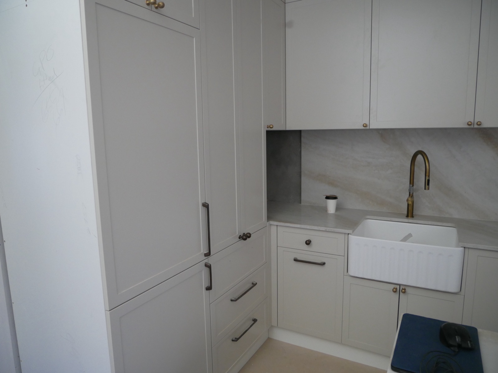New kitchen in the Neutral Bay apartment renovation with shaker cabinetry, fluted farmhouse sink, brass tapware and marble splashback