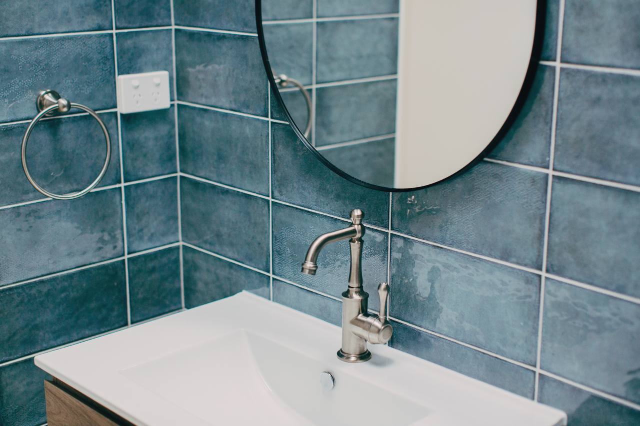 Venetian micro-cement basin and brass tapware against teal tiling in the Pymble bathroom
